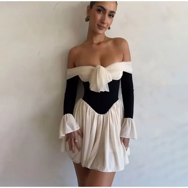 Contrasterende jurk met strik voor en off-the-shoulder design